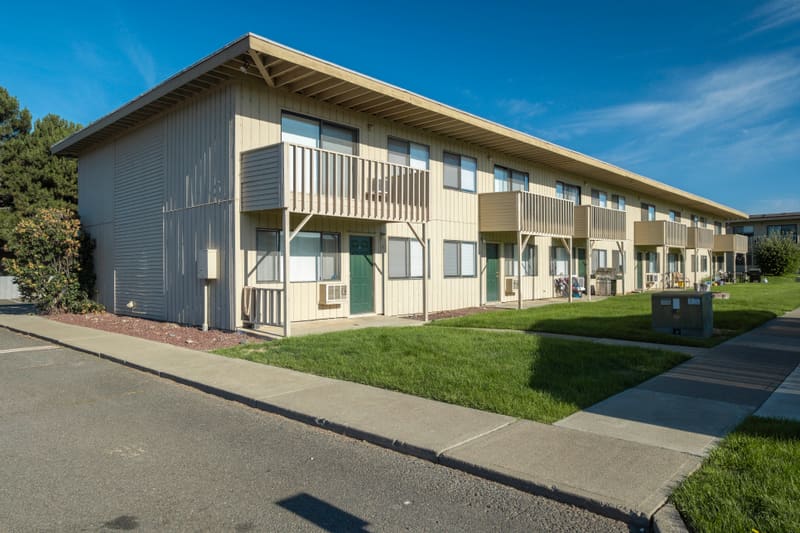 Ground-level view of the apartment buildings and central lawn at Campus Village in Ellensburg